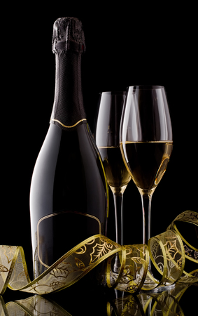 Holiday champagne bottle and two champagne glass on a black with decoration ribbon.の写真素材