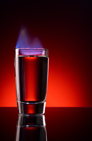 Burning vodka in shot on a red backgroundの写真素材