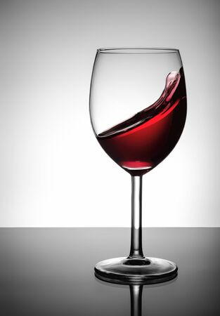 Splashing red wine in glassの写真素材
