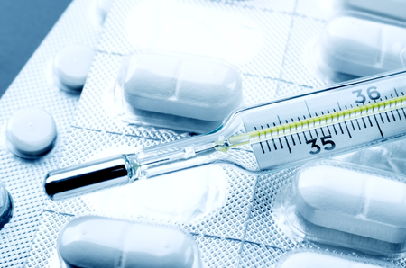 Drug pills and the mercury thermometer close up