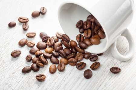 Coffee grains from white cup on a tableの写真素材