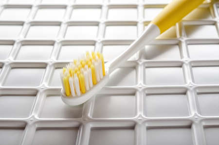 Yellow tooth brush on plastic checkered backgroundの写真素材