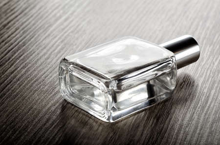 Perfume glass bottle on wooden surface in sunlight.の写真素材