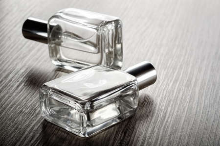 Perfume glass bottles on wooden surface in sunlight.の写真素材
