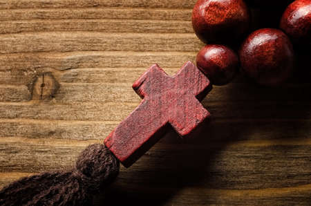 Wooden rosary with christian cross close-up on wooden backgroundの写真素材