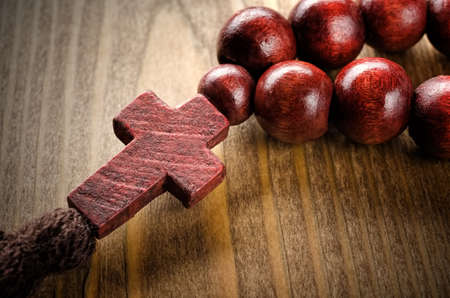 Wooden rosary with christian cross on wooden backgroundの写真素材