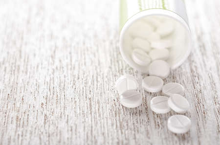 Pills in bottle on wooden background close-upの写真素材