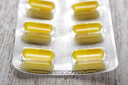 Blister pack of yellow pills on wooden backgroundの写真素材