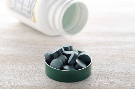 Pills in green cap with bottle close upの写真素材