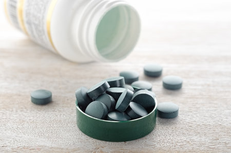 Pills in green cap with bottle close upの写真素材