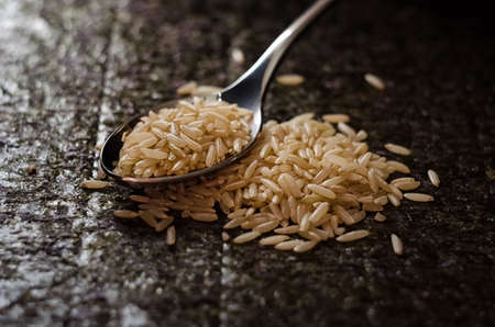 brown rice in metallic spoon closeup