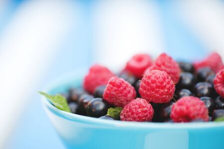 Black currants and raspberries in a bowl close-up