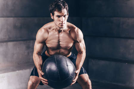 Athlete man practicing wall ball shots with a med ball at the gym. workout.の写真素材