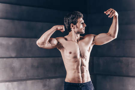 Handsome young muscular man exercising with dumbbells. Bodybuilding and healthy lifestyle concept.
