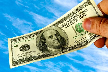 Hand holding money dollars isolated on sky background 