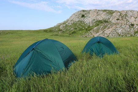 Two tourists tents on meadow in mountainsの写真素材