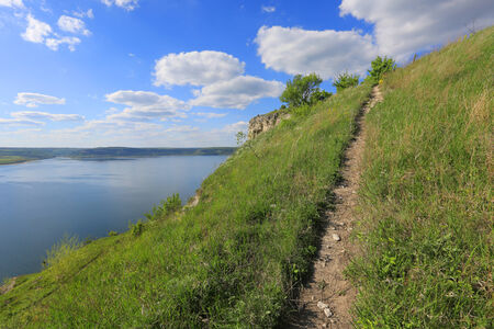 pathway over hill near big lake in nice dayの写真素材
