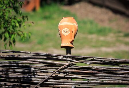 Traditional Ukrainian clay pot on wooden fenceの写真素材