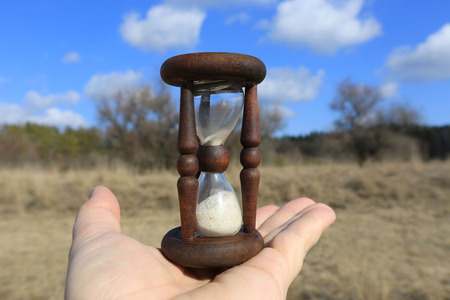Hourglass on man palm against forest background