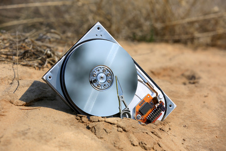 broken hard drive with removed cover in sandsの写真素材