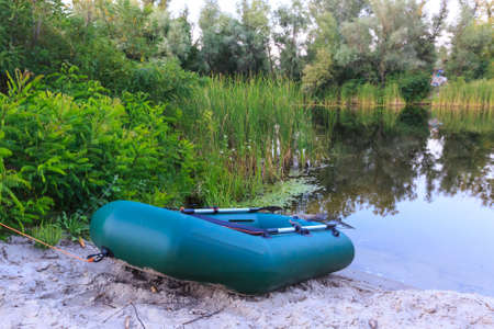 Nice inflatable boat on lake shore in summer forestの写真素材