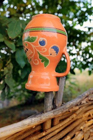Traditional ukrainian clay jug on wooden fenceの写真素材