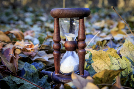 Old hourglass among autumn leafageの写真素材