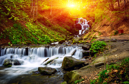 Waterfall on mountain river on sunset backgroundの写真素材