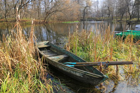 wooden boat on river in autumn parkの写真素材