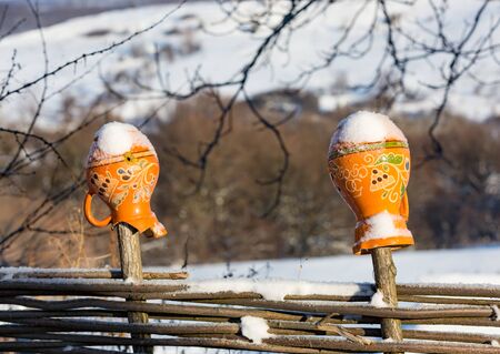 Traditional ukrainian clay jug on fence in winter timeの写真素材