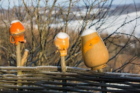 clay jug on wooden fence in winter dayの写真素材
