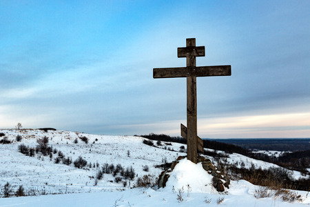 wooden cross on hill top in winter timeの写真素材