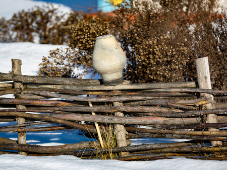 clay jug on wooden fence in sunny winter dayの写真素材