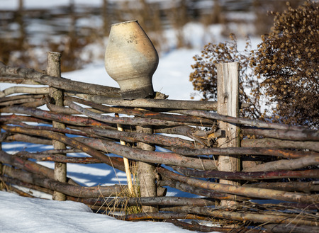 clay jug on wooden fence in winter dayの写真素材