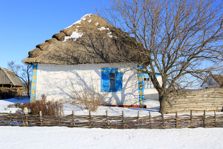 traditional ukrainian house with thatch roof in sunny winter dayの写真素材