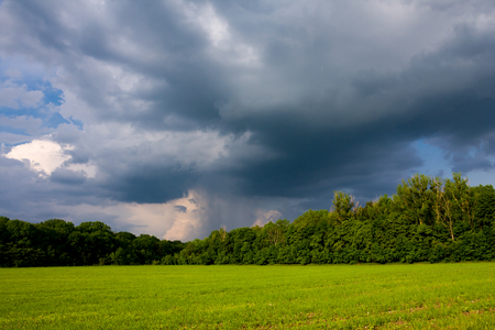 Spring landscape with heavy clouds over the green meadow before the stormの写真素材