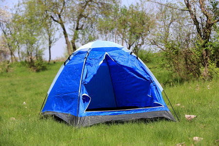 opened tourist tent on green meadowの写真素材