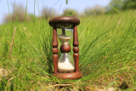 Hourglass on green grass backgroundの写真素材