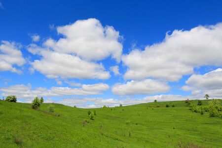 landscape with green hills under nice clouds in skyの写真素材