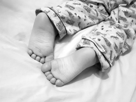 legs of a sleeping child on a bedの写真素材