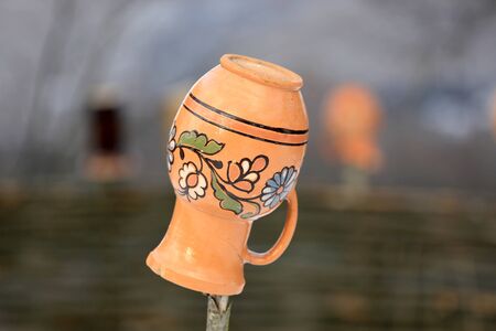 Ukrainian clay jug on a wooden fenceの写真素材
