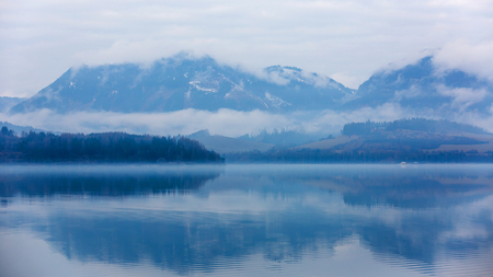 Tranquil landscape with misty mountains and  reflection in lake waterの写真素材