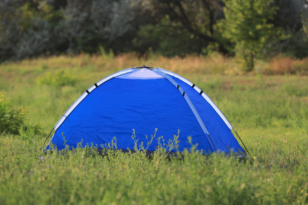 Blue tourist tent on green grasslandの写真素材
