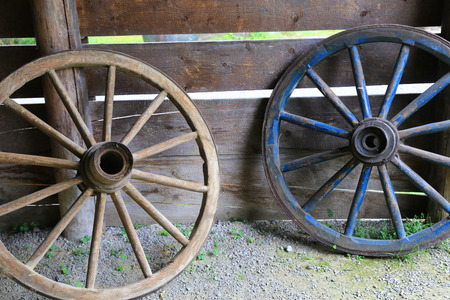 two old wooden wheels on wooden wall backgroundの写真素材