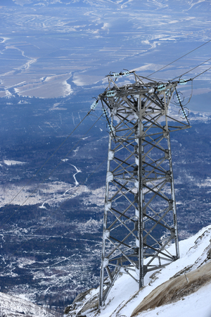 High voltage power line pylon in the mountains in winterの写真素材