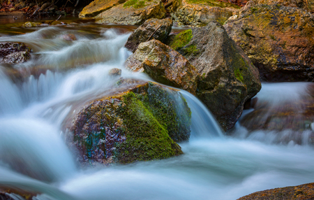 wet stones with green moss in mountain streamの写真素材