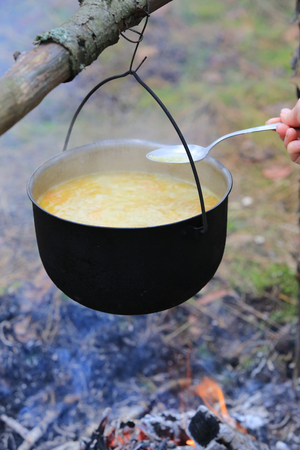 cooking in tourist kettle over campfire in forestの写真素材