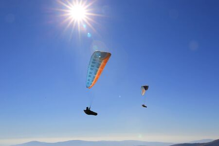 flying paragliders in sky against sunshineの写真素材