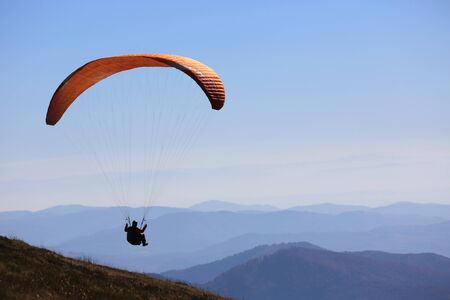 flying paraglider in sky over mountains