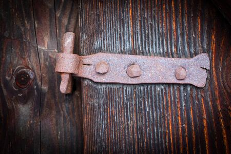 old rusty door hinge on wooden door surface